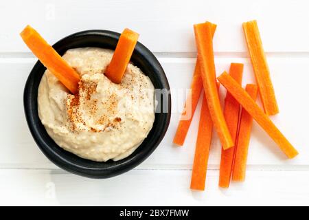 Hummus with carrot sticks.  Top view over white timber. Stock Photo