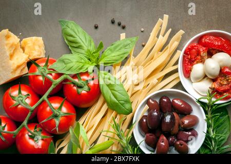 Italian food background, over slate.  Top view. Variety of ingredients, including pasta, tomatoes, basil, olives, parmesan, mozzarella, garlic, and he Stock Photo