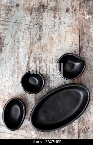 Empty rustic black clay plates over grunge timber.  Top view. Stock Photo