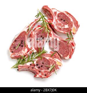 Raw lamb cutlets, top view, isolated, with rosemary and peppercorns. Stock Photo