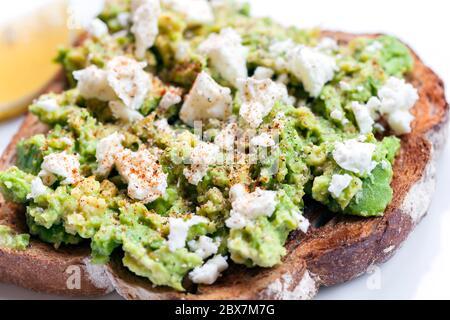 Avocado on toast with feta cheese, lemon and spices. Stock Photo