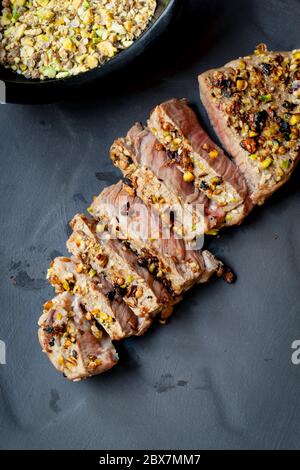 Grilled lamb steak prepared with pistachio dukkah.  On dark slate, overhead view. Stock Photo