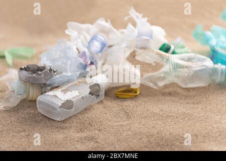 Plastic bottles lies on the beach and pollutes the sea. Spilled garbage on the beach. Empty used dirty plastic. Stock Photo