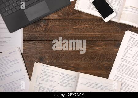 Remote education concept. Open books, smartphone and laptop on wooden desk background, flat lay Stock Photo