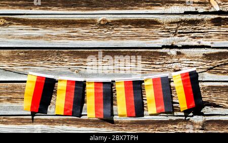 miniature German flags strung along a rope on the exterior wall of an old barn with copy space Stock Photo