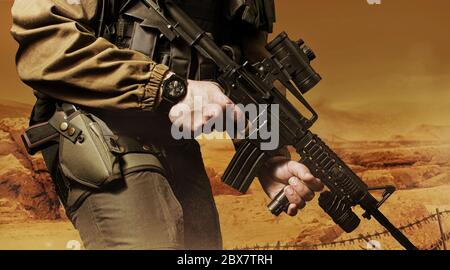 Photo of a soldier in military outfit standing on orange desert background. Stock Photo