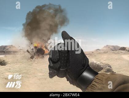 First person view soldier hand in battle gloves & tactical jacket using hand remote to explode target on desert war scene with health & armor indicato Stock Photo