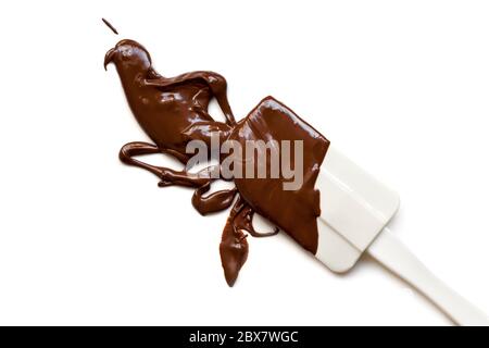 Melted chocolate splashing from a spatula, isolated on white background. Stock Photo