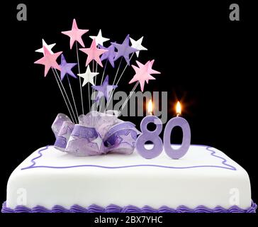Fancy cake with number 80 candles.  Decorated with ribbons and star-shapes, in pastel tones over black background. Stock Photo