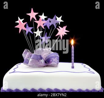 Fancy cake with a single lit candle.  Pastel tones, with ribbons and stars. Stock Photo