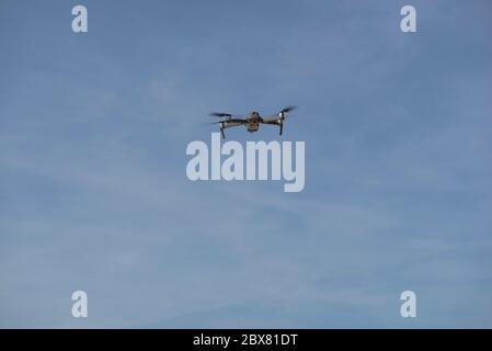 Drone flying in blue sky with clouds in the background. Drone flying overhead in cloudy blue sky. Drone quad copter with high resolution digital camer Stock Photo