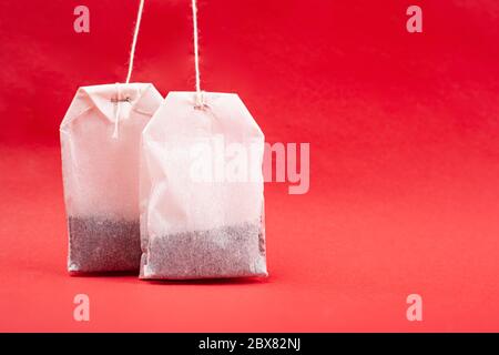 paper white tea bags with copy space on a red background, mockup. Stock Photo