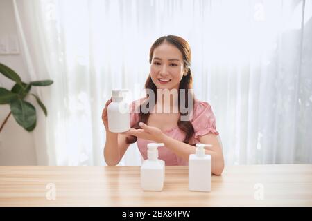 Happy beauty influencer woman showing cosmetics products records video  sitting at home Stock Photo