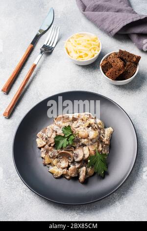 Stewed mushrooms champignons in sauce with sour cream and cheese parsley on a plate Stock Photo