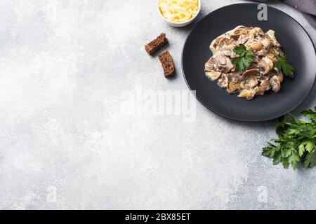 Stewed mushrooms champignons in sauce with sour cream and cheese parsley on a plate Copy space. Stock Photo