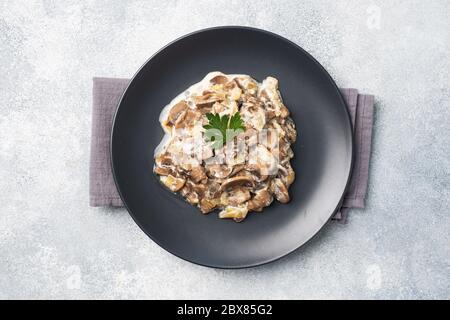 Stewed mushrooms champignons in sauce with sour cream and cheese parsley on a plate Copy space. Stock Photo