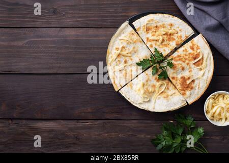 Pieces of quesadilla with mushrooms sour cream and cheese on a plate with parsley leaves. Wooden background copy space Stock Photo