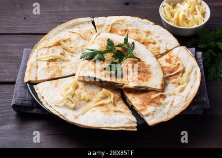 Pieces of quesadilla with mushrooms sour cream and cheese on a plate with parsley leaves. Wooden background copy space Stock Photo