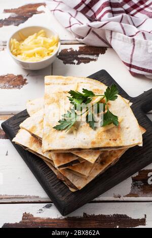 Pieces of quesadilla with mushrooms sour cream and cheese on a wooden stand with parsley leaves. Wooden background copy space Stock Photo