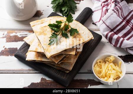 Pieces of quesadilla with mushrooms sour cream and cheese on a wooden stand with parsley leaves. Wooden background copy space Stock Photo