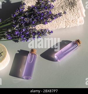 Lavender flowers and essential oils in glass bottles, soap bar on light grey background, top view. Copy space Stock Photo
