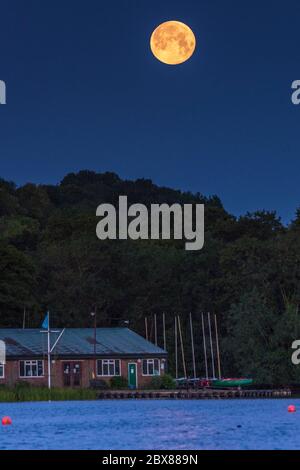 Rickmansworth, UK.  6 June 2020. UK Weather - June's full moon, known as a Strawberry Moon, sets at Rickmansworth Aquadrome in north west London.  June's full moon, according to The Old Farmer's Almanac, was the signal for Native American Algonquin tribes to harvest wild strawberries.  This month's full moon also coincides with a subtle penumbral eclipse, which occurs when the Earth casts a slight shadow over the Moon.     Credit: Stephen Chung / Alamy Live News Stock Photo