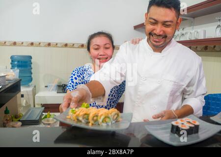 happy Asian couple cooking together -  home kitchen lifestyle portrait of Chinese cheerful and sweet husband and wife making delicious traditional Jap Stock Photo