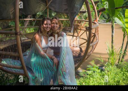 beautiful and happy girlfriends after outdoors yoga workout - two young pretty women smiling cheerful enjoying tropical jungle after fitness drill in Stock Photo