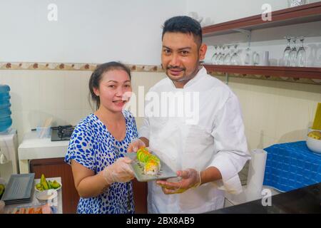 happy Asian couple cooking together -  home kitchen lifestyle portrait of Chinese cheerful and sweet husband and wife making delicious traditional Jap Stock Photo