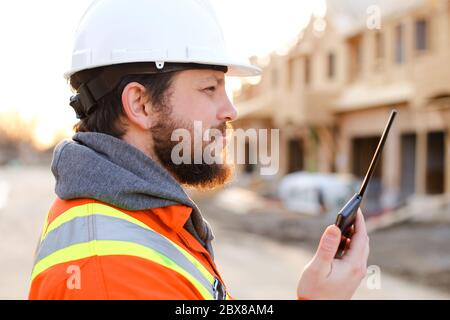 Portrait of european foreman talking by walkie talkie on construction site. Stock Photo