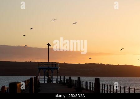 Weymouth, UK. 6th June, 2020. The early morning sunrise over the Stone Pier in Weymouth Bay. Stock Photo