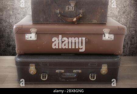 Old Vintage Suitcase in retro room on the floor, three piled suitcases background Stock Photo