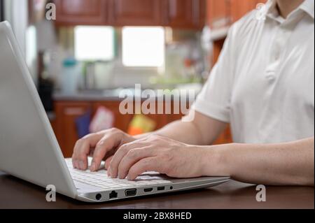 A middle-aged man who is dressed casually at home and works from home using a computer. Internet network connecting, telecommuting concept. Stock Photo