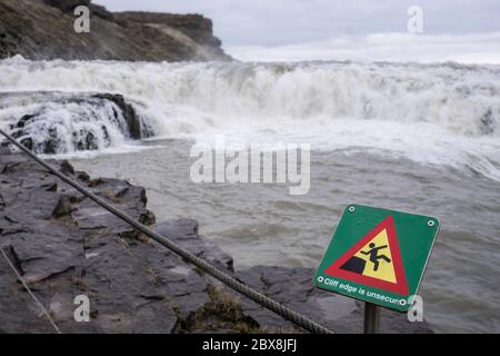 Sign (Cliff edge is unsecur) near the Gulfoss waterfall in the Golden Circle in South Iceland. The sign is in focus Stock Photo