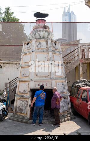 Two chinese men standing at the ceremonial furnace used for burning, offering of joss paper Rong Kuak Shrine, Bangkok, Thailand, Southeast Asia. Stock Photo