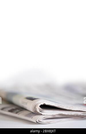 Folded newspapers on white table with narrow depth of field. Vertical image. Copy space Stock Photo