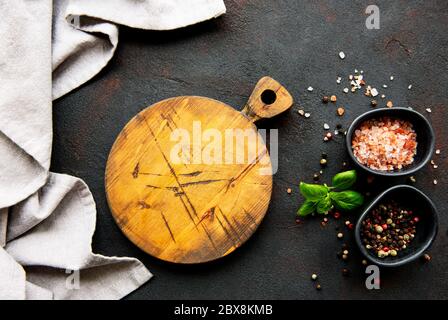 Chopping board, seasonings and  on dark concrete background Stock Photo