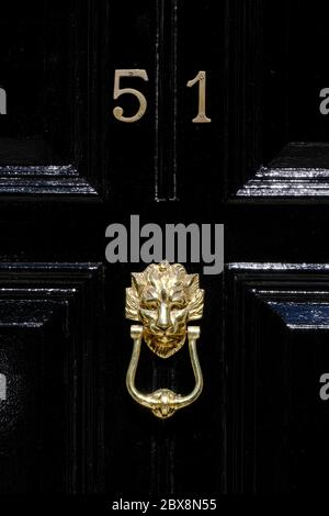 A brass lion's head door knocker on a black door Stock Photo