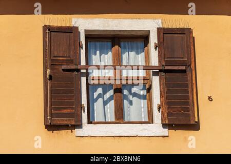Close-up of a window with open brown wooden shutters with spike steel sticks to prevent birds from stopping, especially pigeons, residential building Stock Photo