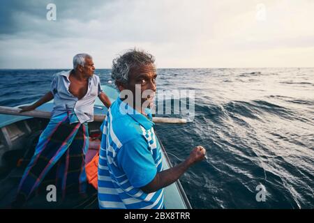 Hard work on sea. Two fishermen on fishing boat near coastline of Sri Lanka. Stock Photo