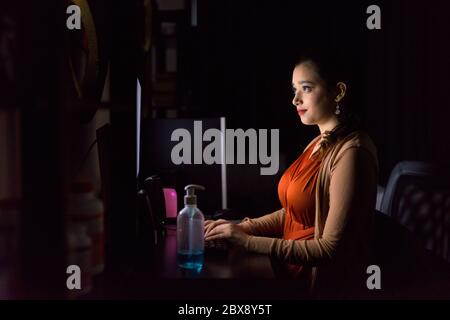 Young beautiful Indian woman working from home late at night in the dark Stock Photo