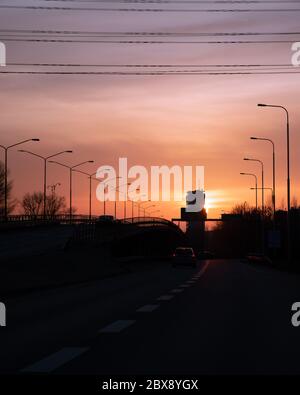 Driving on the highway towards a skyscraper with the sun setting behind it in Malmö, Sweden Stock Photo