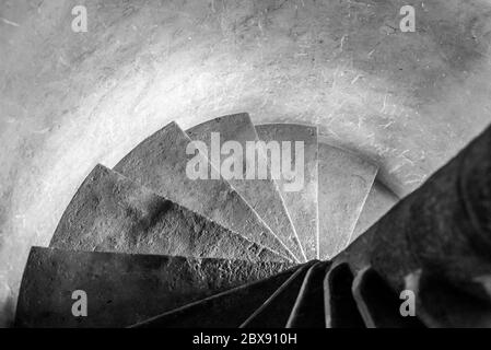 Old stone narrow spiral staircase inside the medieval tower. Black and white image. Stock Photo