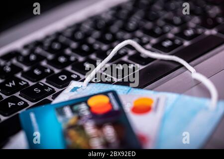 Work from home concept due to Covid-19 or Coronavirus with laptop medical mask and credit cards. Selective focus image. Stock Photo