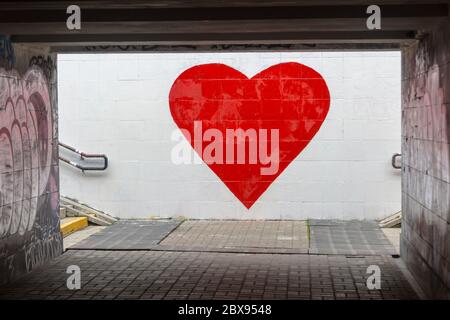 A big red heart is painted on a white wall. Street graffiti, street art expressing love Stock Photo