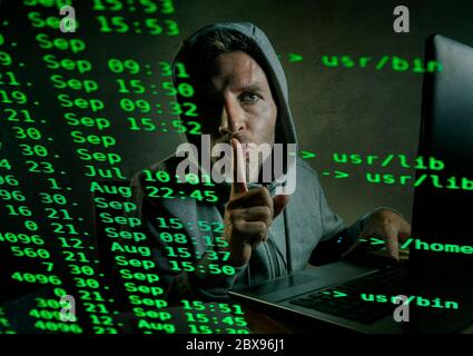 computer programmer man in hoodie hacking system entering code typing on laptop hacking and decoding system data illegal access breaking password on c Stock Photo
