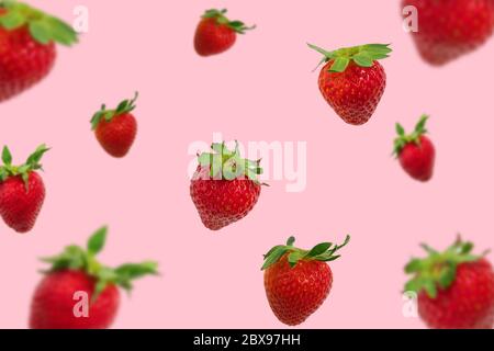 Colorful pattern of falling strawberries on pastel pink background, strawberry background Stock Photo