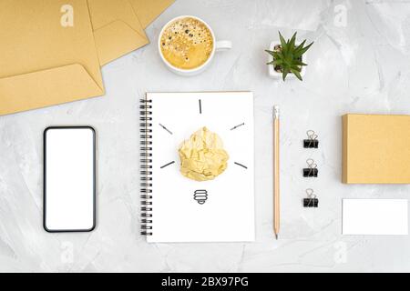 Refreshment break idea and productivity boost concept. Flat lay of an office workplace with a smartphone, coffee cup, light bulb symbol made of a crum Stock Photo