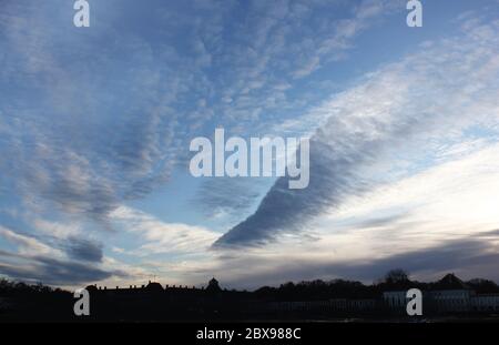 Dramatically sharp wedge shaped cloud formation over a palace silhouette at sunset. Unique arrow or triangle cloud structure. Dynamic sky backdrop. Stock Photo
