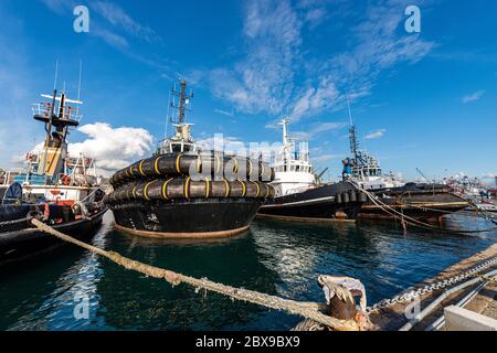 Four tugboats moored in the port of La Spezia, tied with hawsers to the quay. Liguria, Italy, Europe Stock Photo